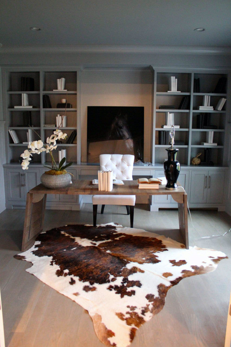 Large tri color spotted cowhide rug in room